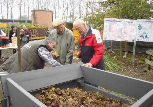Foto van drie mannen die kijken naar een compostbak